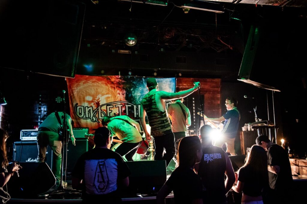 Energetic band performance on stage with vibrant lights and audience interaction.